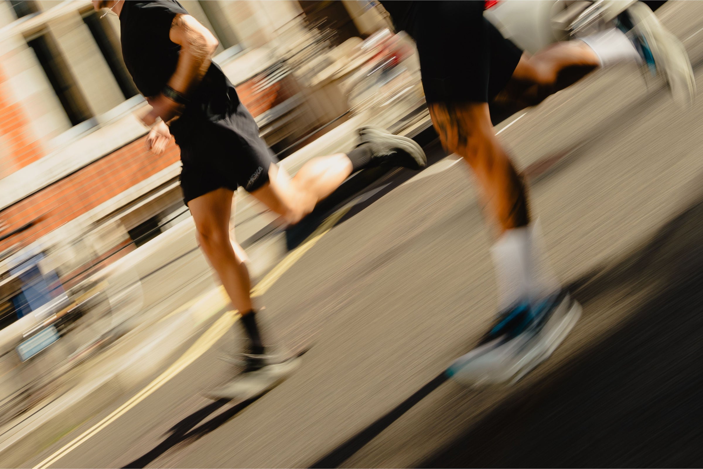 Two runners in motion on a city street wearing black and white POP Running Co performance socks.